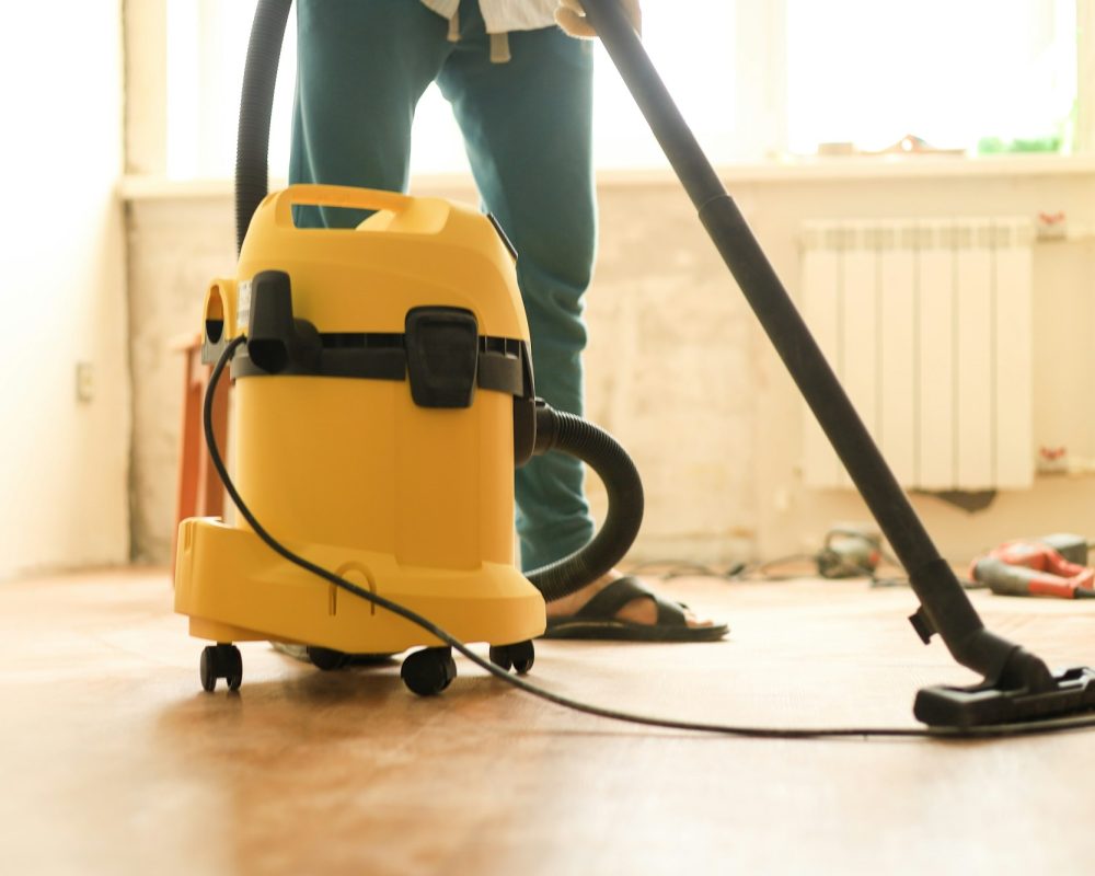 A man is cleaning the room during repairs using a construction vacuum cleaner