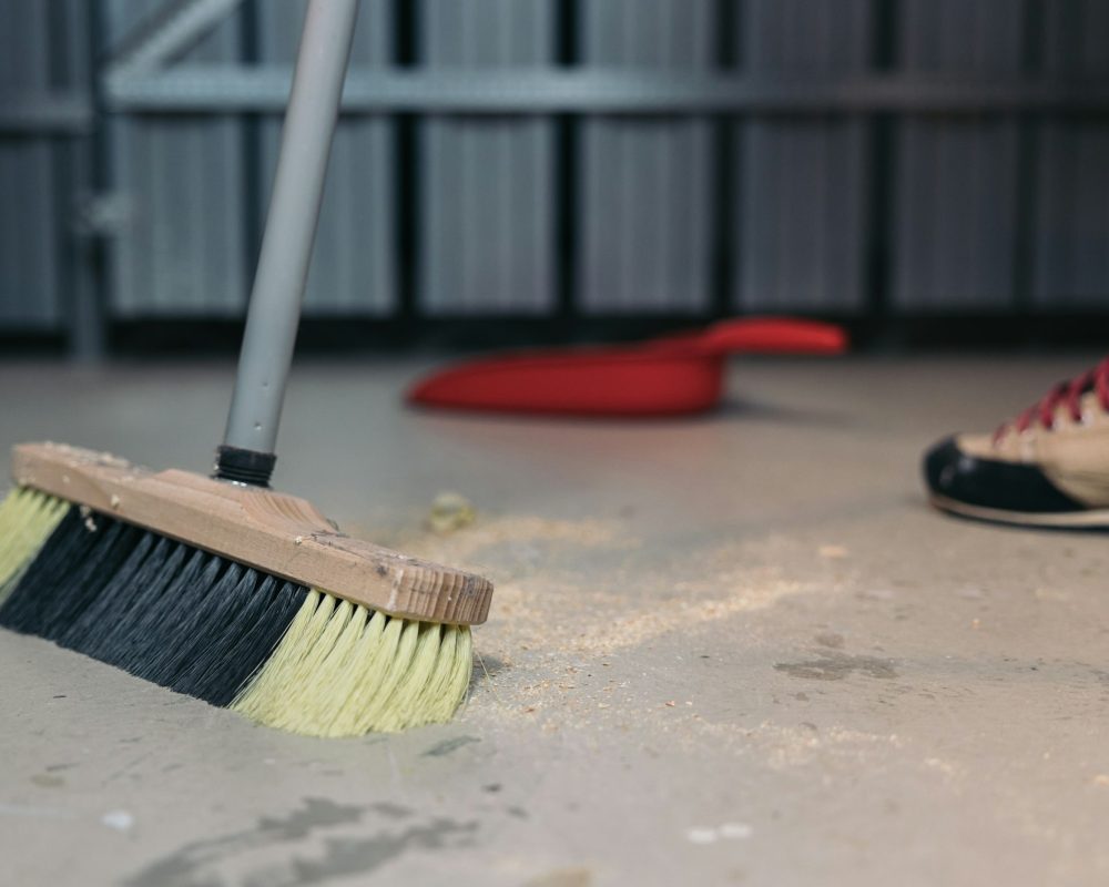 Cleaning sawdust from the floor with a broom. Cleaning up trash after work